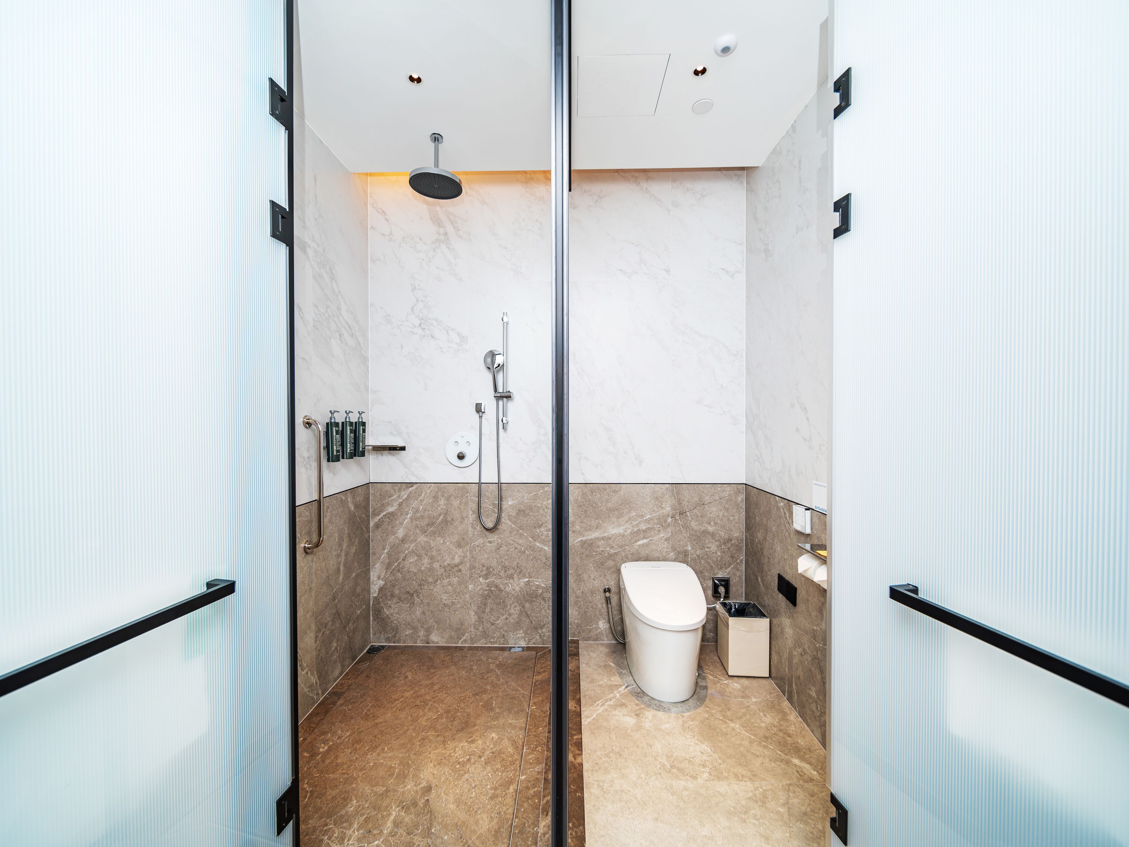 A modern bathroom with a glass shower enclosure, a toilet, and a sink.