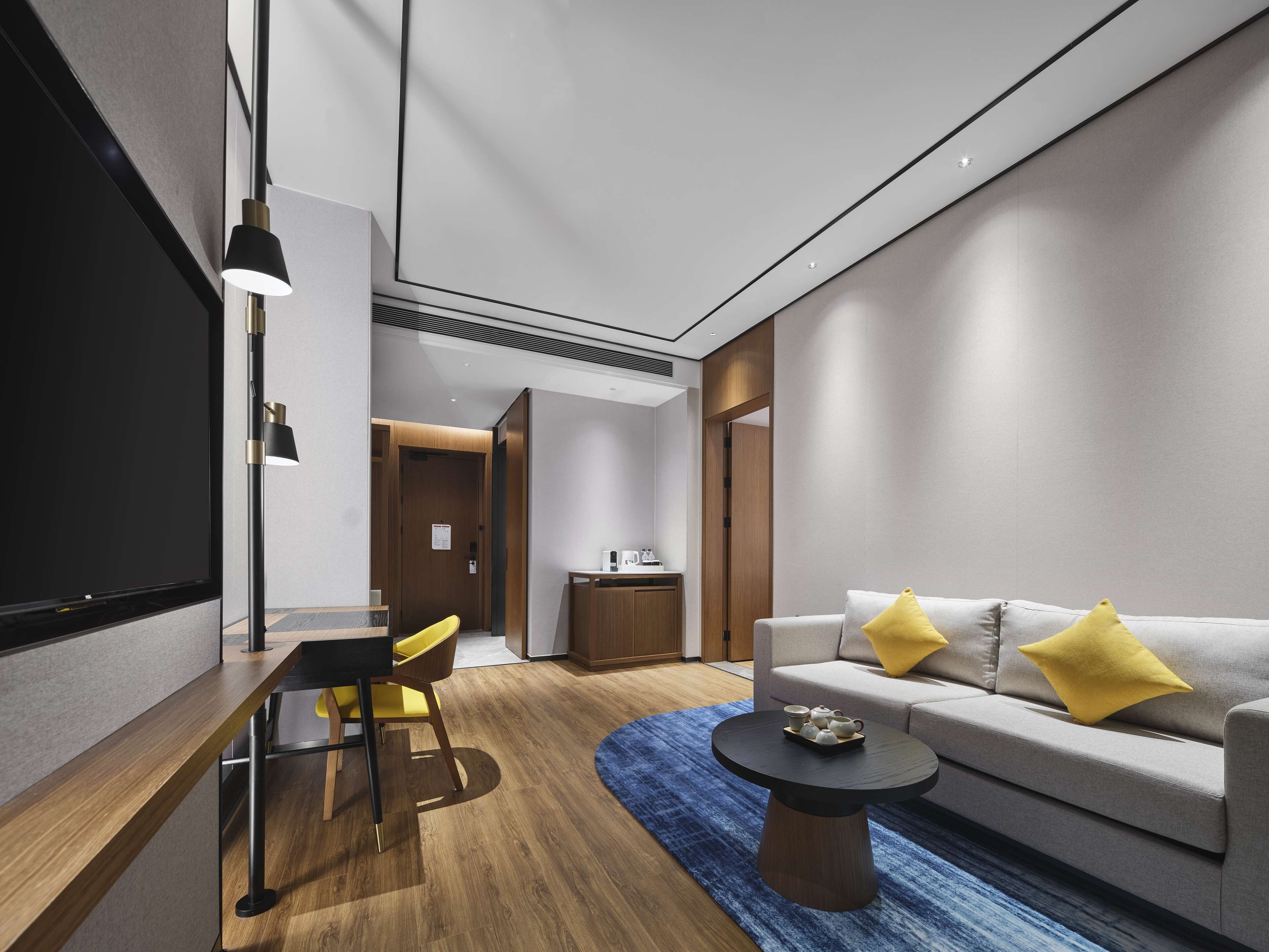 Una habitación de hotel moderna con un sofá, una mesa de centro y un comedor con sillas.
