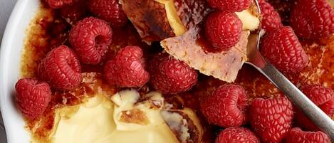 A dessert with raspberries and a scoop of ice cream in a white bowl.