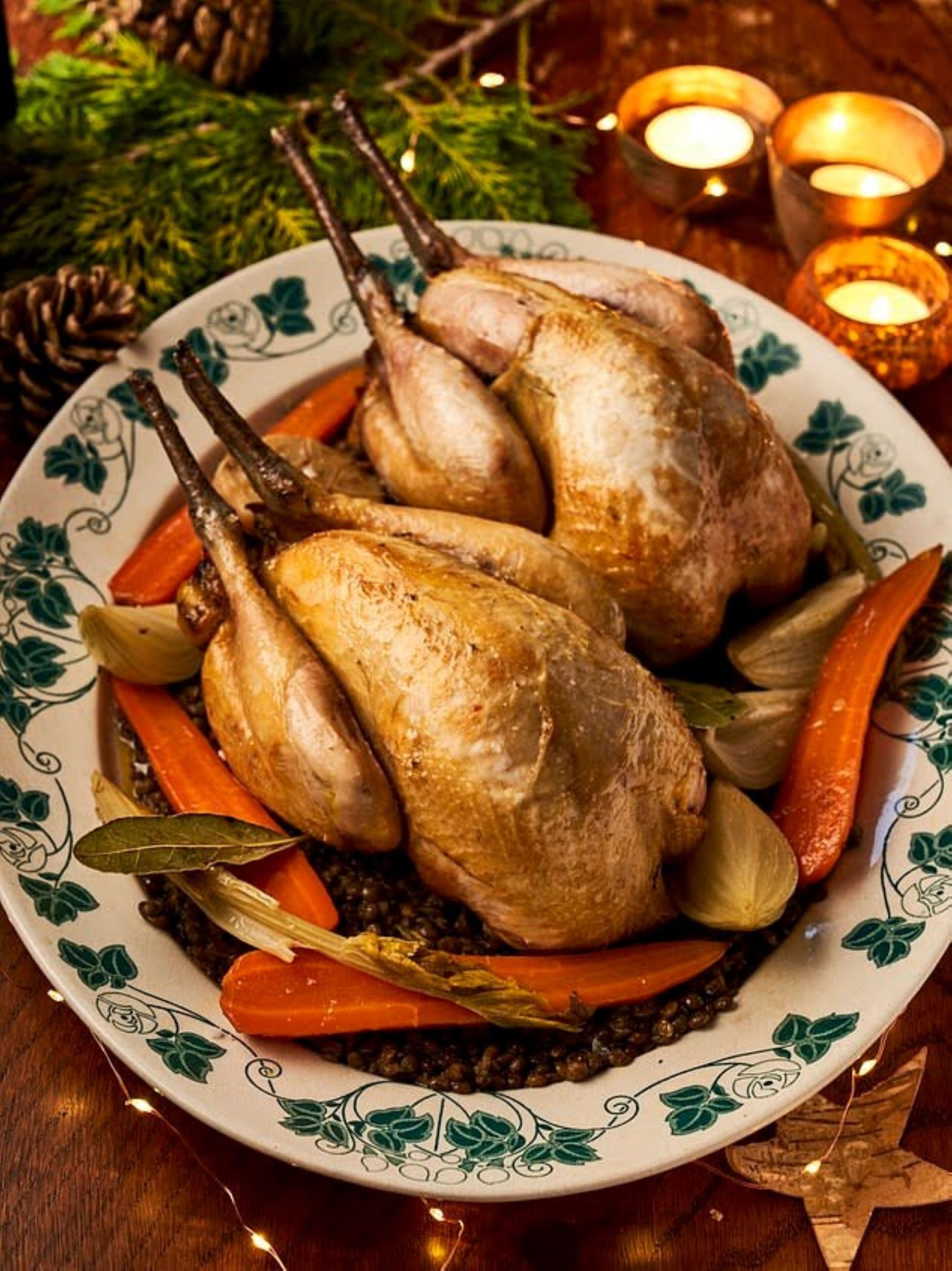 A plate with roasted quails, carrots, and herbs.