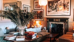 A cozy living room with a fireplace, a large painting, and a variety of books and decorative items.