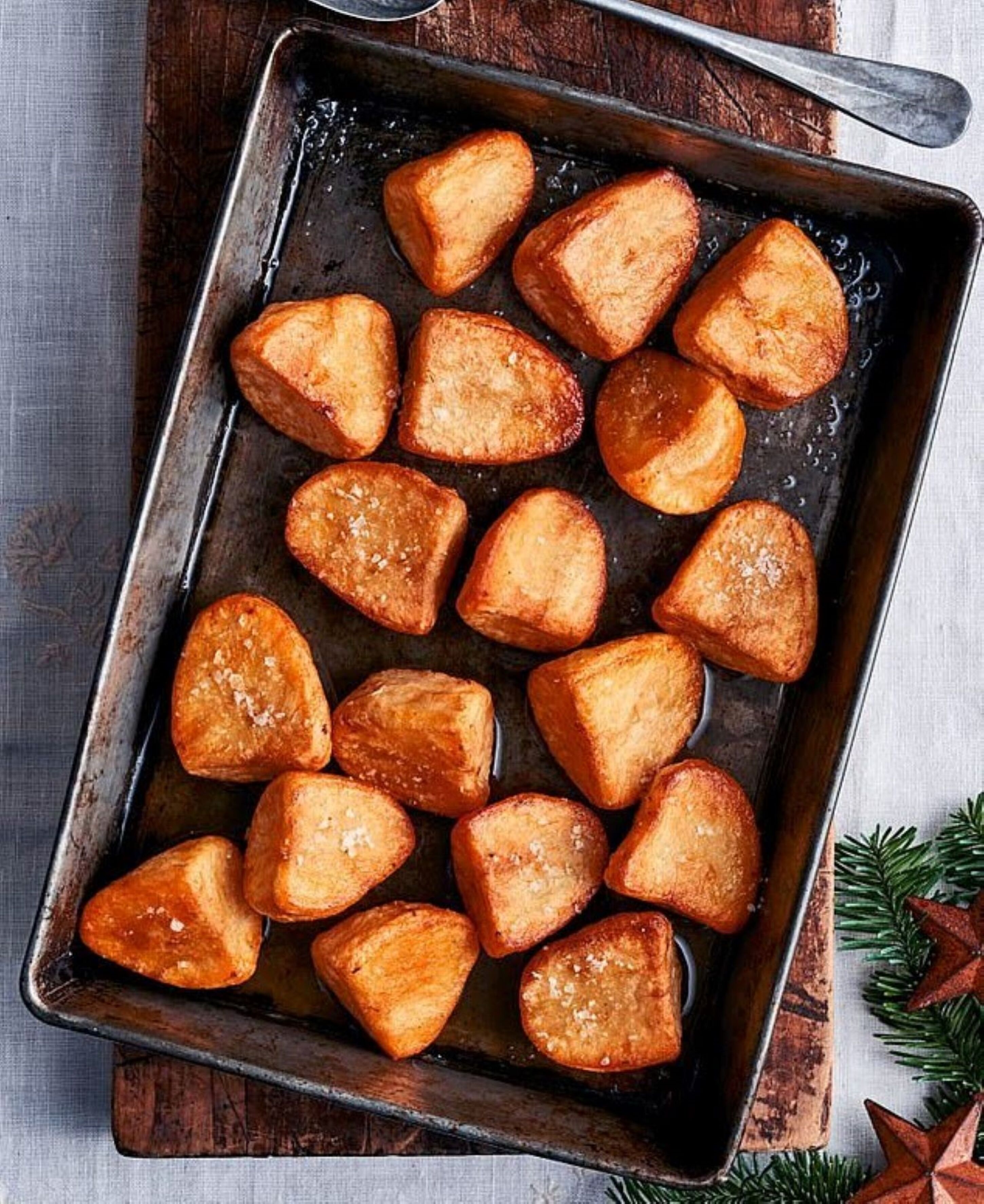 A rectangular baking tray with golden-brown potato wedges.