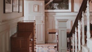 A hallway with a patterned carpet, wooden cabinets, and a staircase with white balusters.