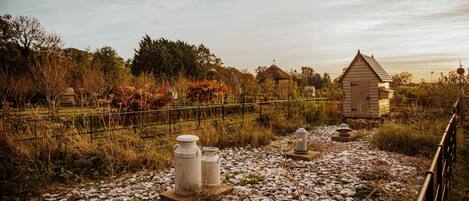 A rustic outdoor area with a gravel path, stone structures, and a small wooden building.