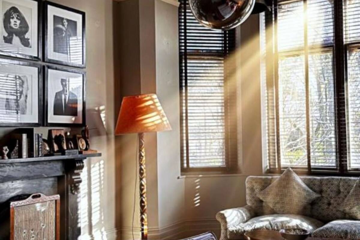 A hotel room with a bed, a chair, a lamp, and a wall with framed pictures.