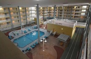 Un hôtel à plusieurs étages doté d’une piscine centrale, de nombreux balcons et d’une terrasse sur le toit.
