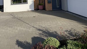 Ett modernt hus i två våningar med ett garage, en liten trädgård och en asfalterad uppfart.