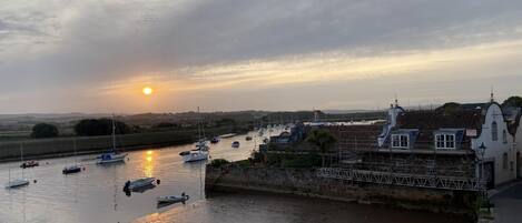 A harbor with boats, a sunset, and buildings with traditional architecture.