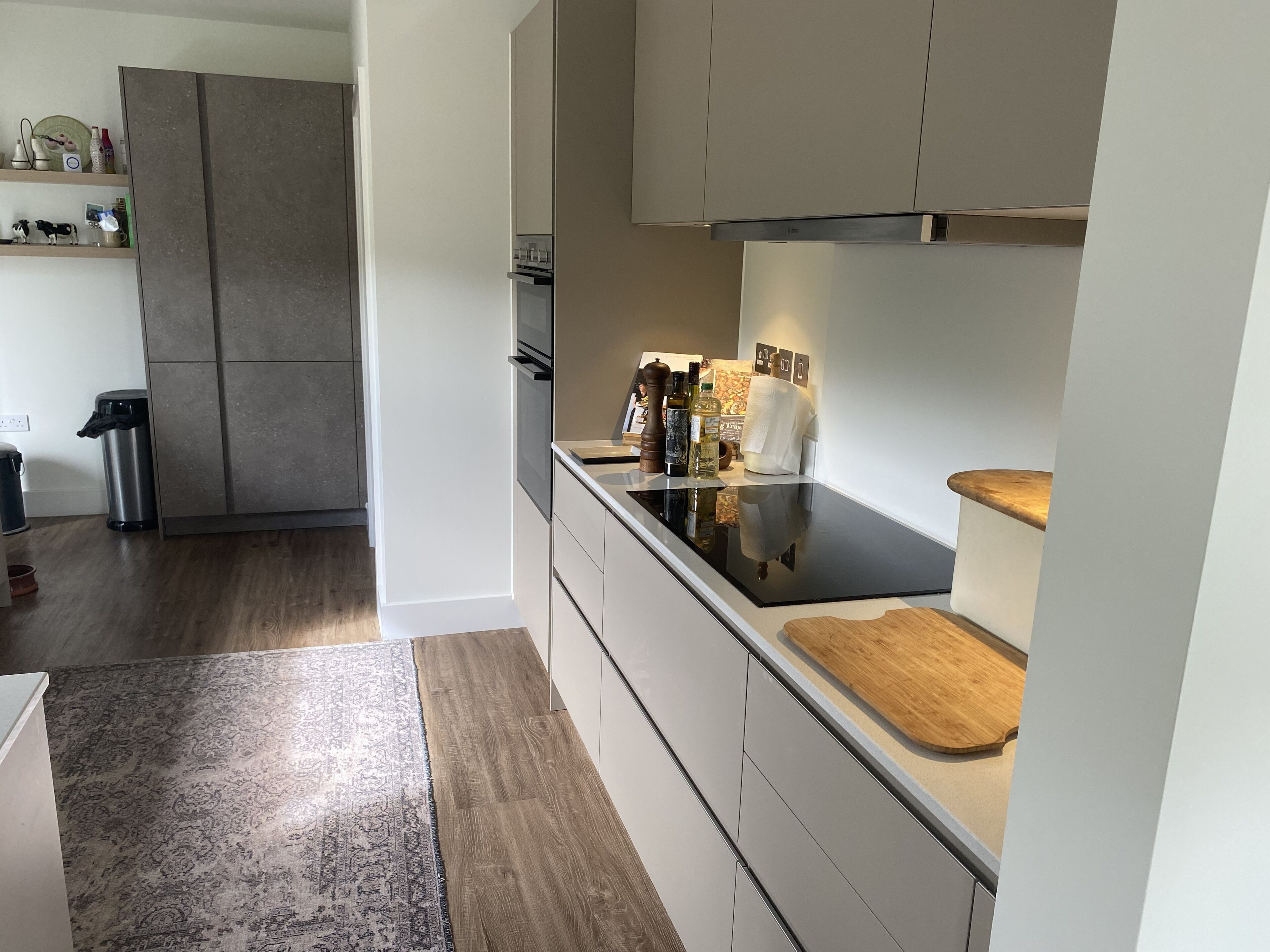 Eine moderne Küche mit schwarzem Arbeitsplatz, Schneidebrett aus Holz und Edelstahlgeräten.