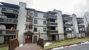 A multi-story residential building with balconies, a central entrance, and a wooden deck. - Gateway Condo Unit 25 - 12 to 15 minute drive to Killington Mountain (Mendon)