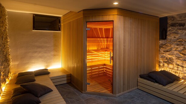 A sauna with wooden benches and a stone wall. - La Posteria Junior Suite 1 by icasamia.it (Orino)