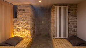 A spa room with stone walls, a wooden bench, and a shower area. - La Posteria Junior Suite 1 by icasamia.it (Orino)