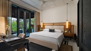 Habitación de hotel con cama, mesitas de noche, escritorio y vistas a zonas verdes.