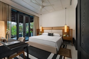 Ein Hotelzimmer mit Bett, Nachttischen, einem Schreibtisch und Blick auf Grünfläche.