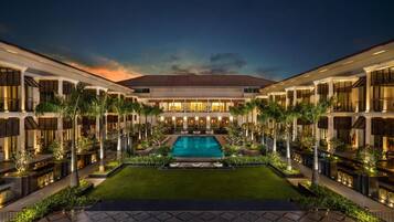 A hotel with a central pool, multiple guest rooms, and a well-maintained garden.
