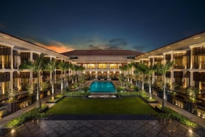 Ein Hotel mit einem zentral gelegenen Pool, mehreren Gästezimmern und einem gepflegten Garten.