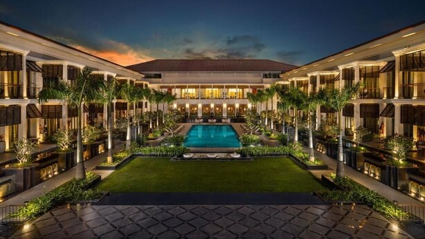 Un hotel con piscina central, varias habitaciones de huéspedes y un jardín bien cuidado.