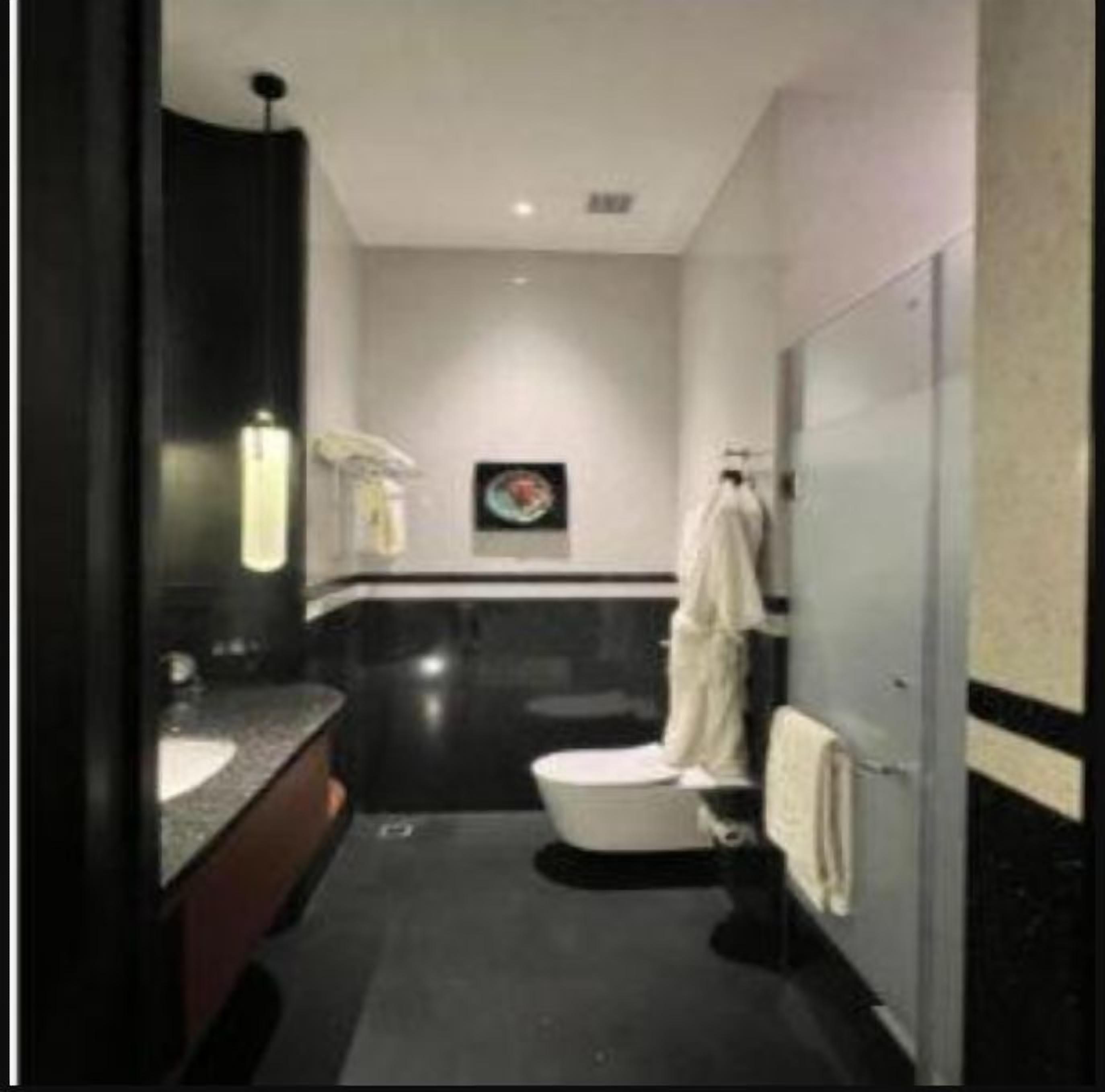 A modern bathroom with a dark floor, a white toilet, a sink with a mirror, and a towel rack.