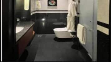 A modern bathroom with a dark floor, a white toilet, a sink with a mirror, and a towel rack.