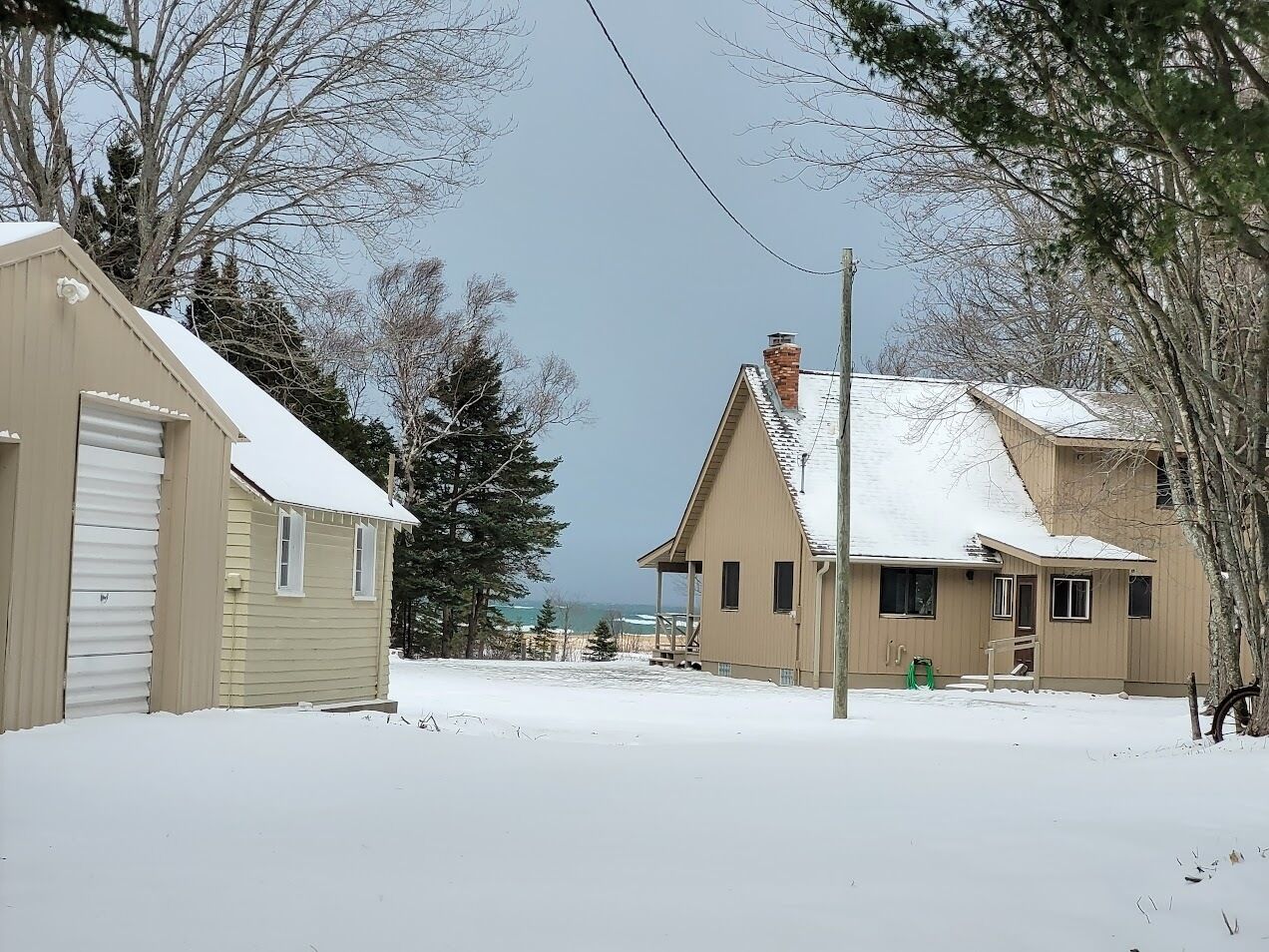 A snow-covered residential area with two houses, one beige and one brown, and a garage.