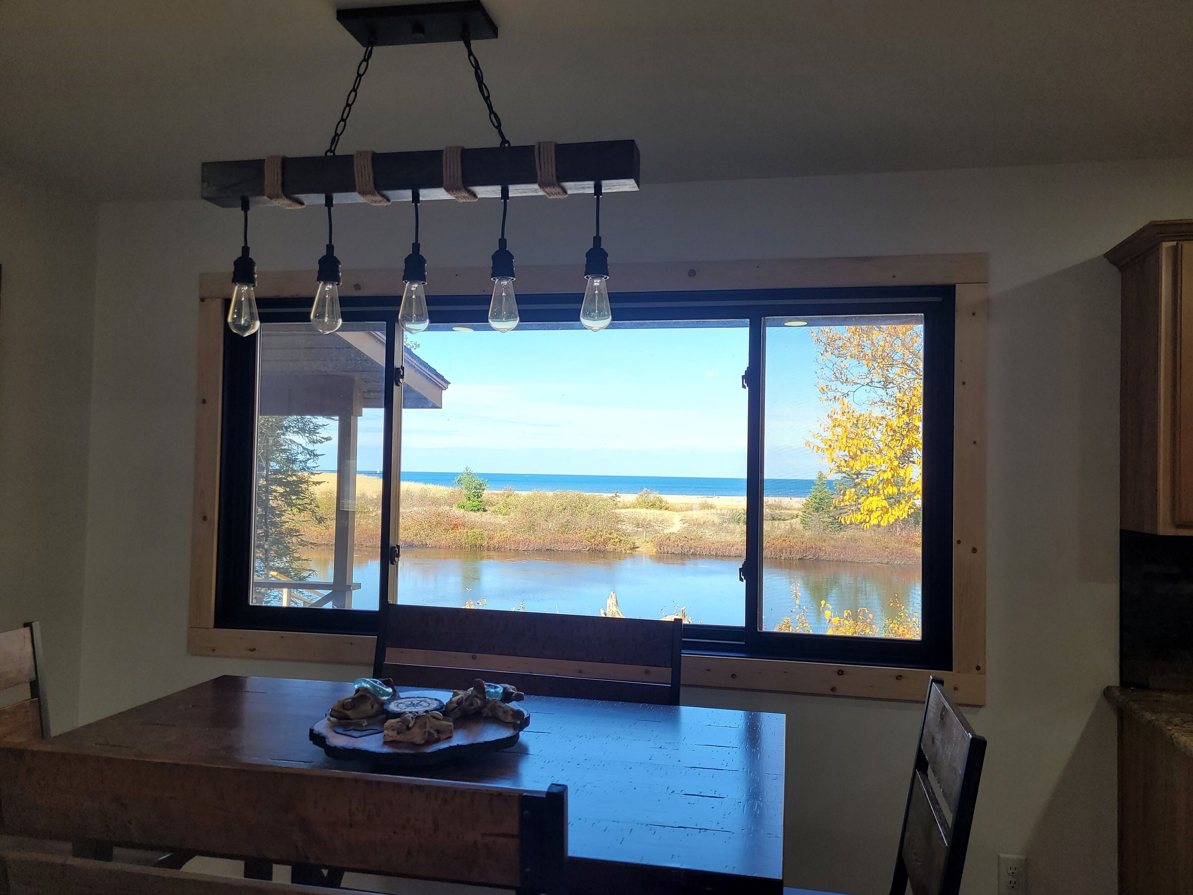 Un comedor con un gran ventanal con vistas al agua y a una playa.