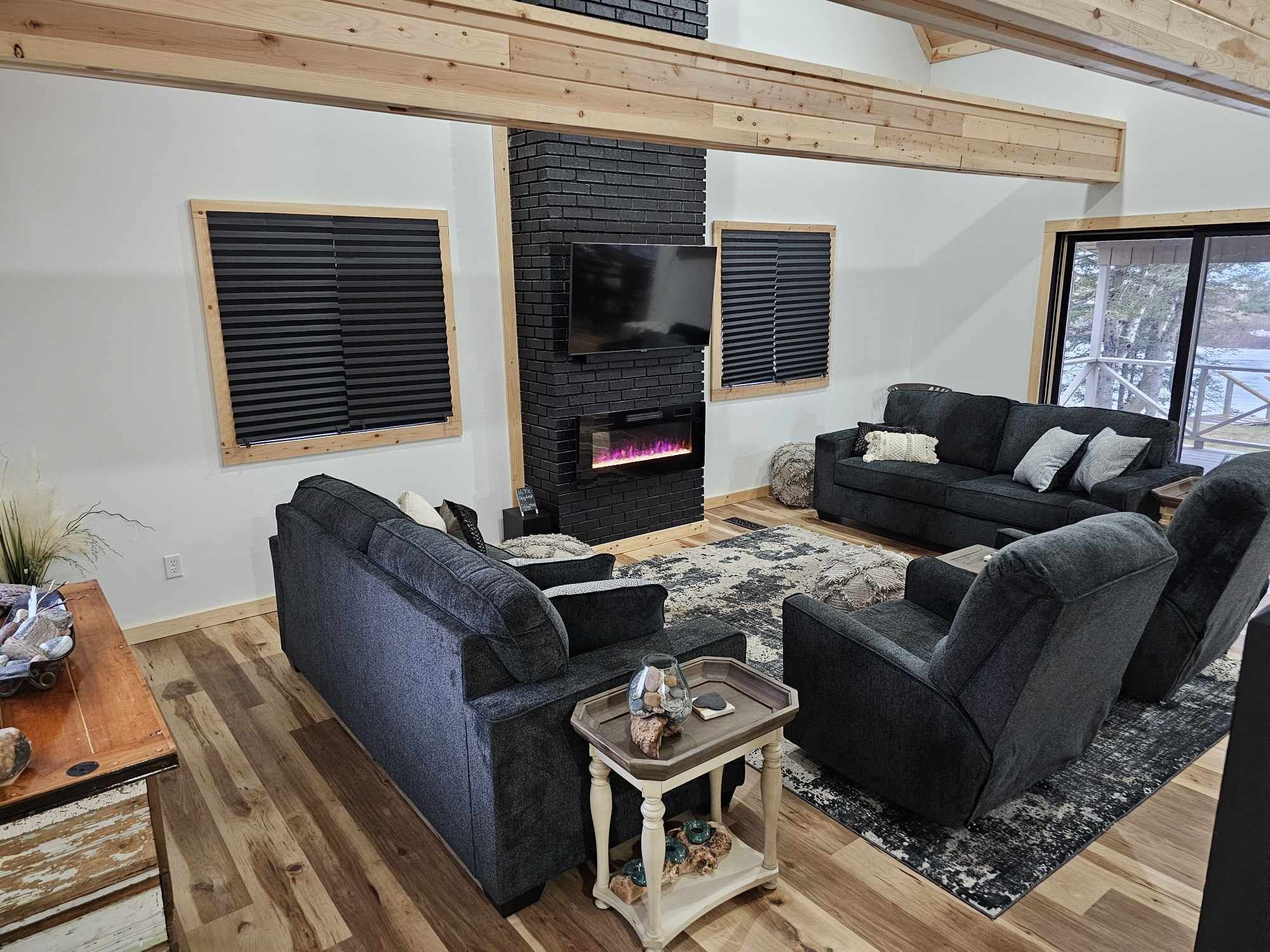 A modern living room with a fireplace, two sofas, a coffee table, and a TV mounted on the wall.