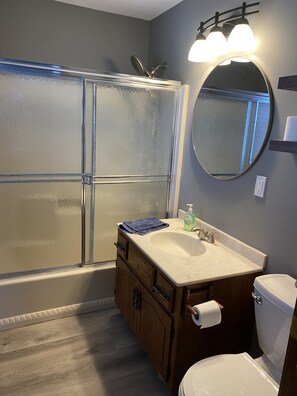 A bathroom with a glass shower enclosure, a sink with a mirror, and a toilet. - NEW Beautiful, Spacious Lake House (Angola)
