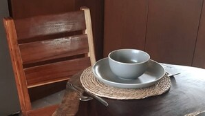Ein Holzhocker mit einer gewebten Tischmatte und einer Schüssel auf einem Tisch.