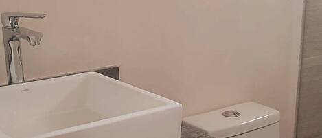 A bathroom with a white sink, a toilet, and a marble countertop.
