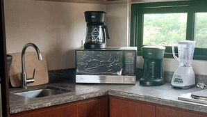 Eine Küche mit Mikrowelle, Kaffeemaschine und Mixer auf der Arbeitsplatte.