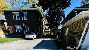 A residential street with houses, a driveway, and a parked car. - Entire 3 Bedroom Cozy Unit (Waukegan)