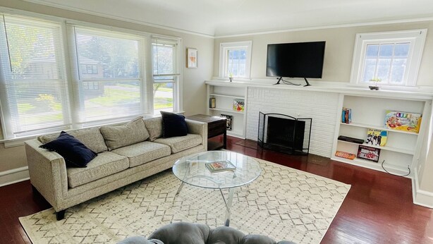 A living room with a sofa, a glass coffee table, a fireplace, and a TV. - Entire 3 Bedroom Cozy Unit (Waukegan)
