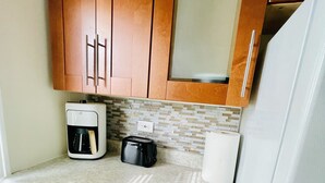 A compact kitchen with wooden cabinets, a coffee maker, a toaster, and a refrigerator. - Entire 3 Bedroom Cozy Unit (Waukegan)