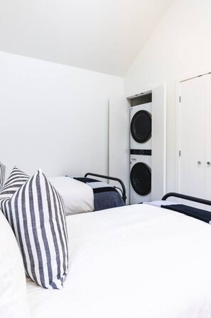 A bedroom with a bed, two pillows, a wardrobe, and a washing machine.