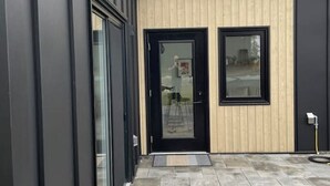 Un bâtiment moderne à l’extérieur noir, doté d’une section recouverte de panneaux en bois et d’un patio carrelé.