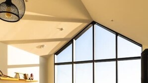 Un salon moderne avec une grande fenêtre, un canapé, une table basse et un téléviseur.