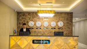 A reception desk with a "Reception" sign, multiple clocks, and a stone wall backdrop.
