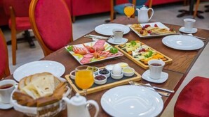A breakfast table set with plates, bread, and various breakfast items.