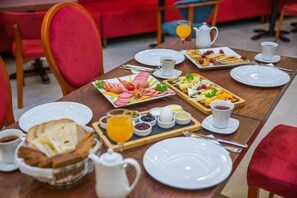 A breakfast setting with plates, cups, and a tray of food. - Grand Midway Hotel (Baku)