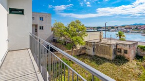 Un balcon avec vue sur un port de plaisance, des bâtiments et un ciel dégagé.