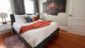 Un dormitorio con cama, mesita de noche, lámpara, alfombra y puerta.