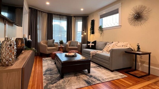 Una sala de estar moderna con sofá, sillón, mesa de centro y televisor.