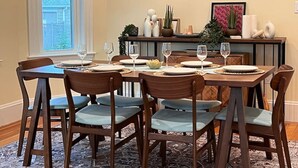Comedor con una mesa rectangular dispuesta para seis personas, rodeada de sillas de madera con asientos acolchados.