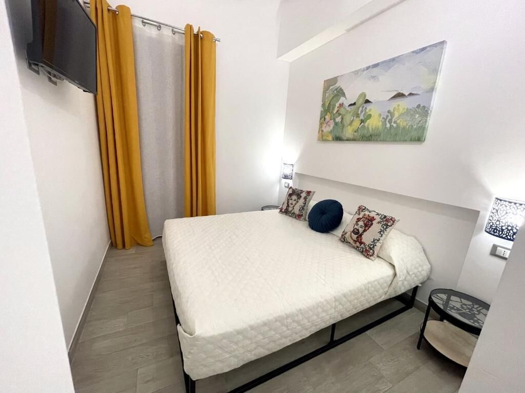 Una camera da letto con un letto, tende, un quadro e un tavolino.