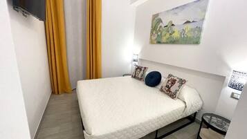 Una camera da letto con un letto, tende, un quadro e un tavolino.