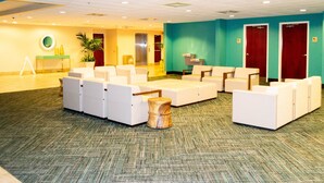Eine Lobby mit Sitzbereichen, einer Rezeption und einer Pflanze.