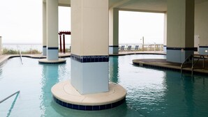 Ein Innenpool mit klarem Wasser, umgeben von Säulen und einer gefliesten Liegefläche.