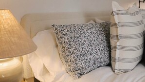 A neatly made bed with patterned pillows, a bedside lamp, and a framed picture on the wall. - The Lake Room - #12 (Whitehall)