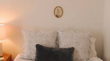 A bed with white bedding, a dark pillow, and a wall-mounted picture.