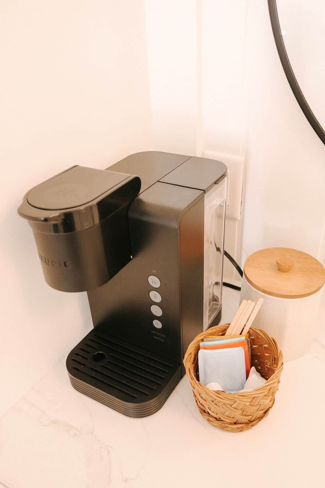 A coffee maker with a basket of items beside it.